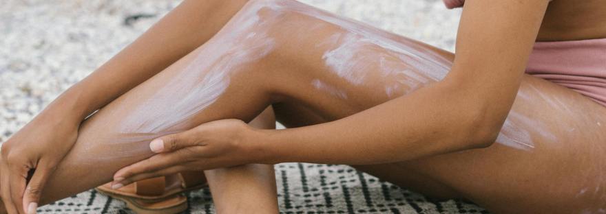 woman seated on textile applying suncsreen